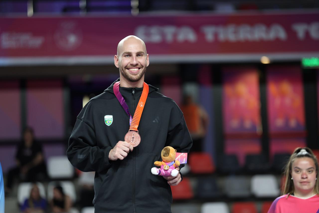 Carateca com quimono branco posa com medalha