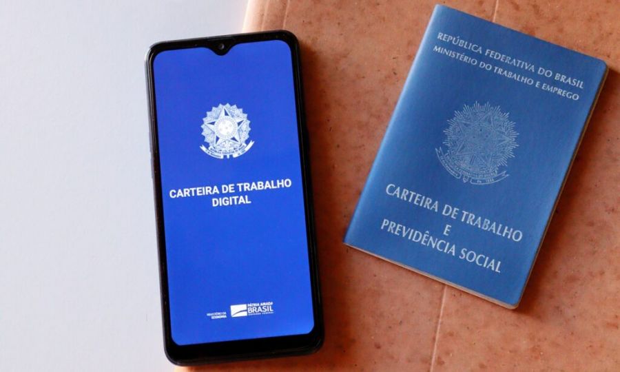 Carteira de trabalho digital em celular ao lado da carteira de trabalho física