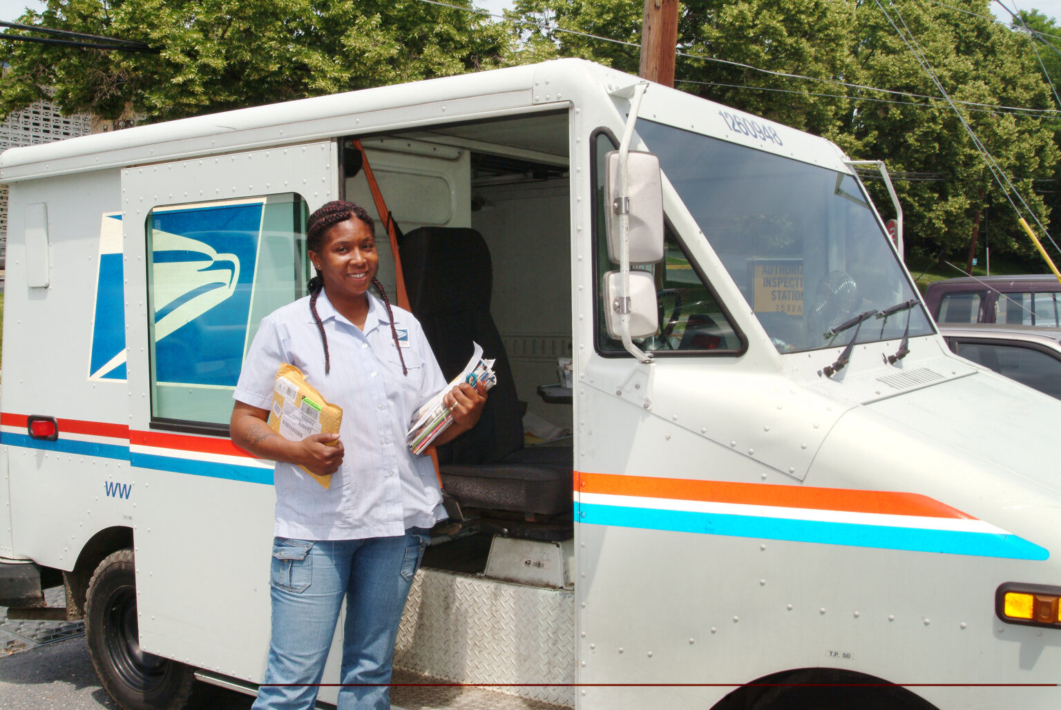 Trabalhadora postal ao lado de veículo de entrega