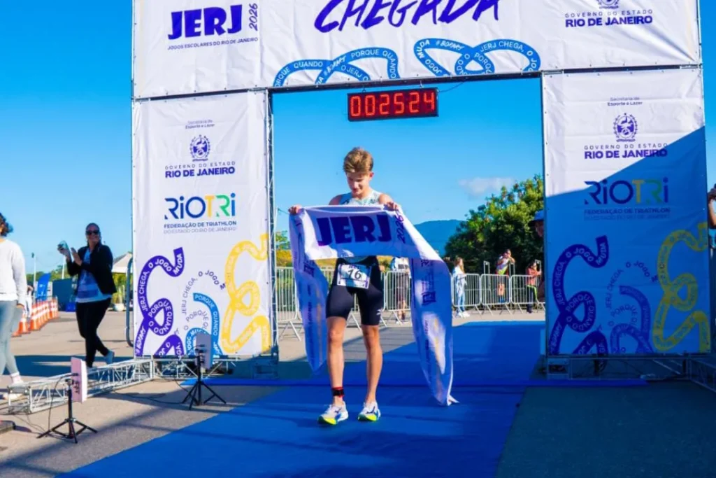 Atleta do Time RJ segura faixa de chegada em evento esportivo escolar do Rio de Janeiro