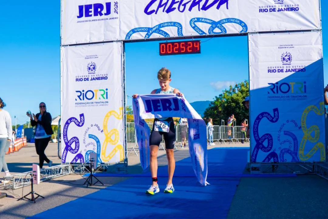 Atleta do Time RJ segura faixa de chegada em evento esportivo escolar do Rio de Janeiro