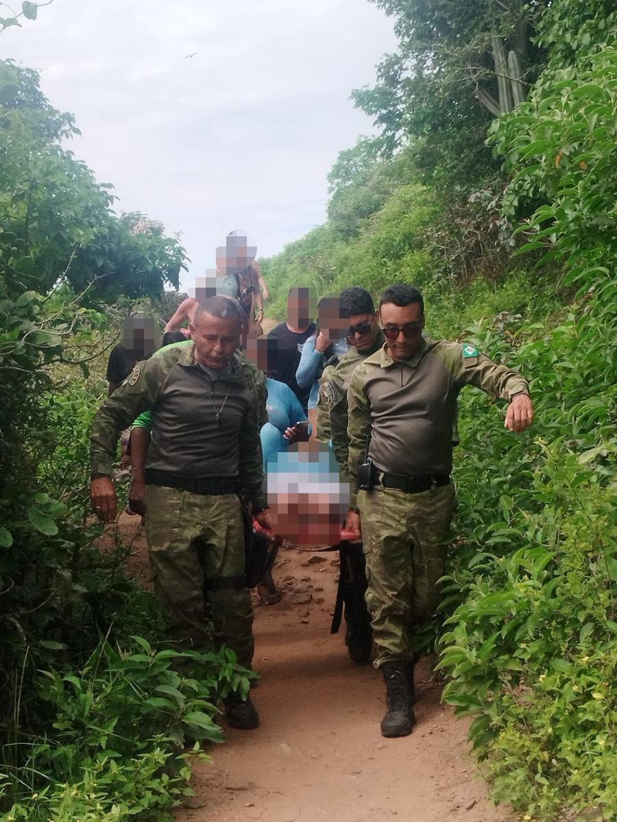 Agentes do GOPAM transportam uma pessoa durante resgate em trilha de Arraial do Cabo, com identidade da vítima preservada